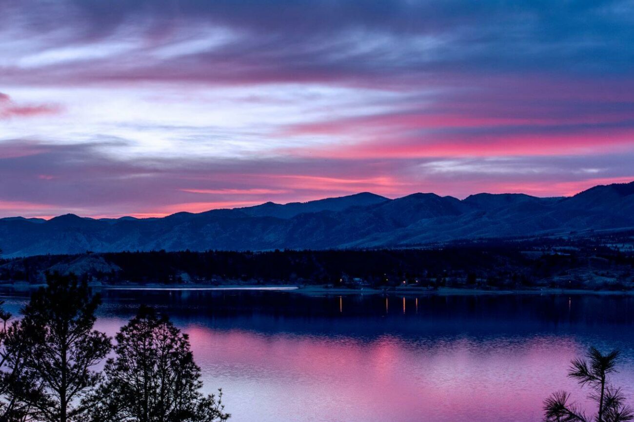 A peaceful sunset over Canyon Ferry Lake in Montana with vivid pink and blue hues in the sky reflected in the water