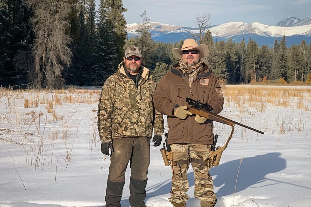 Two elk hunters decked in hunting gear pose for a photo in the snow in Montana. 