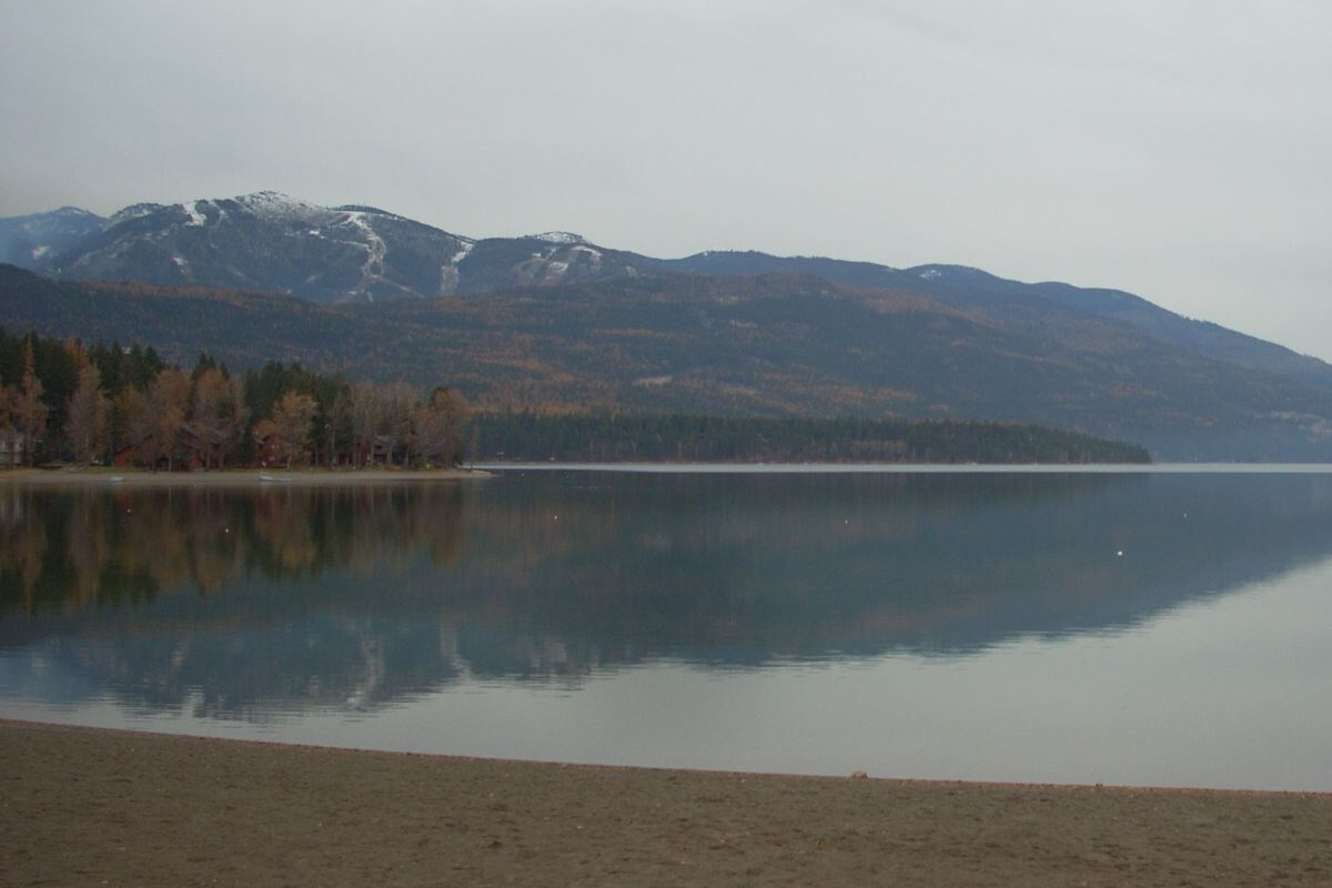 Experience the picturesque beauty of a Whitefish lake in Montana with stunning views of majestic mountains in the background, making it an ideal destination for outdoor enthusiasts looking for exciting fall activities.