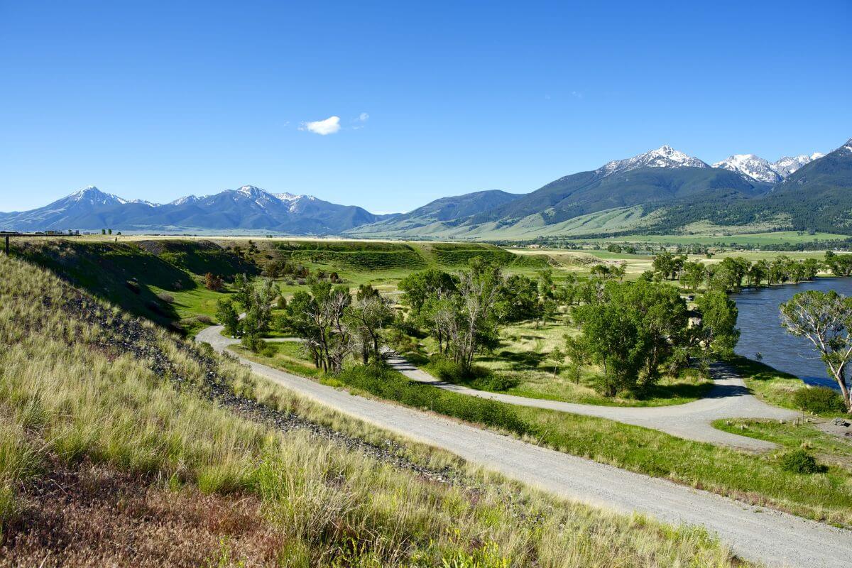 A road leading to a river with mountains in the background in Montana