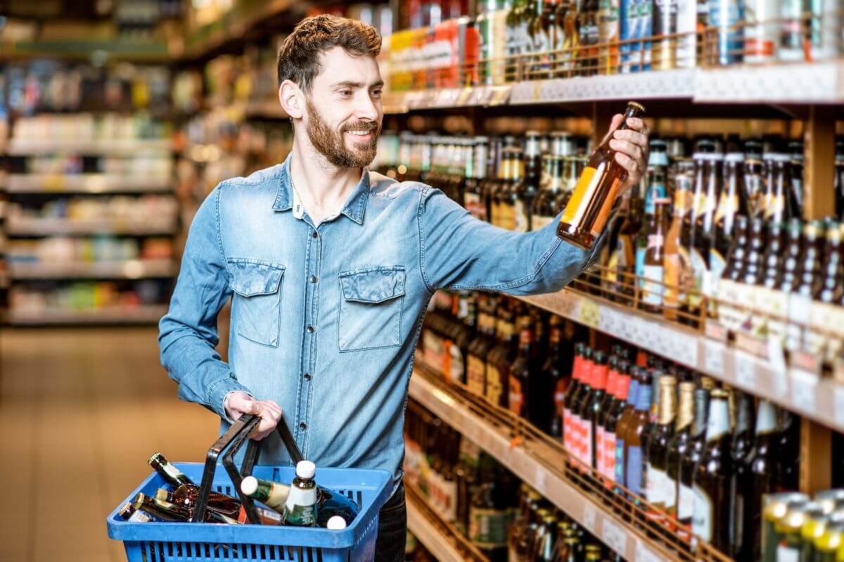 A man holding a basket full of beer bottles in a supermarket
