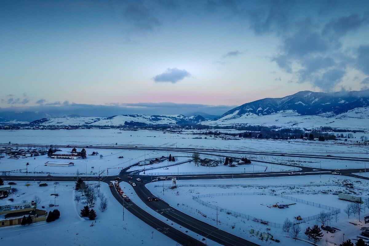 An aerial view of a snowy road and mountains in Montana.