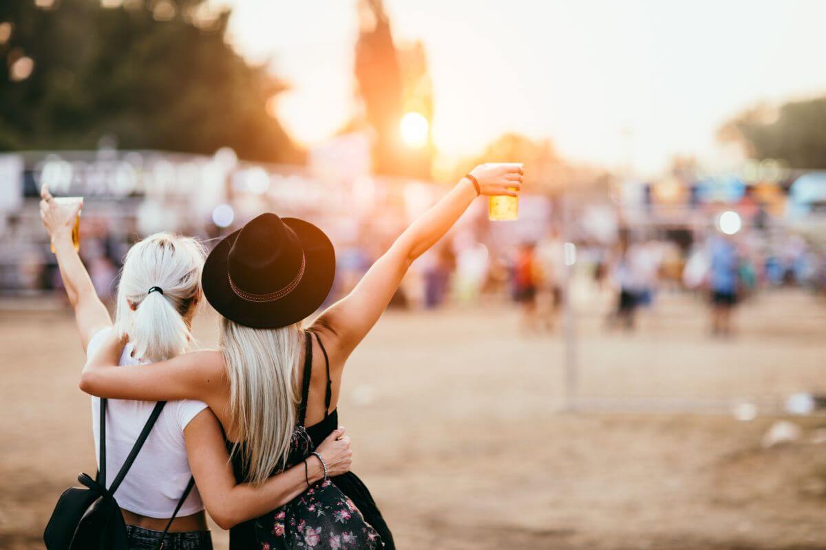 Two women raising their arms at a festival