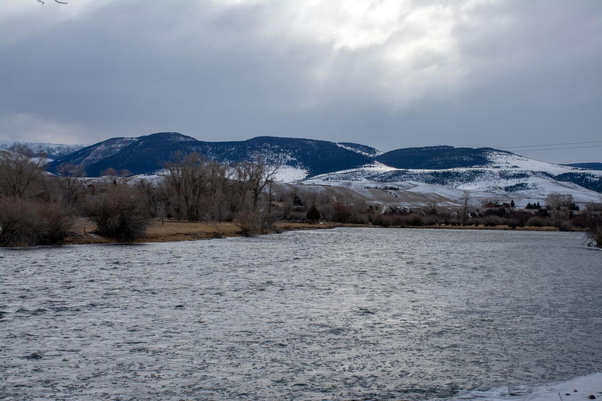 A river in Montana during a rainy spell with snow-capped mountains in the background.