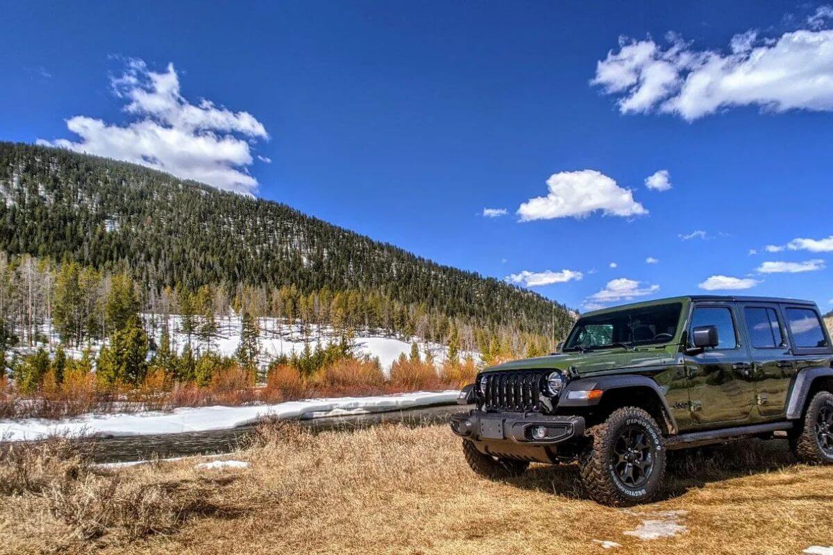 A green jeep from Rocky Mountain Expeditions parked in a grassy clearing during a jeep tour through the Rocky Mountains.