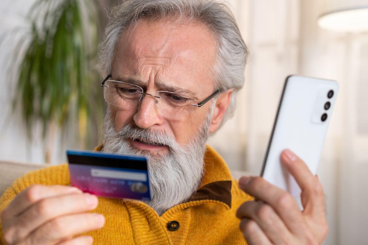 A man with a beard holding a credit card.