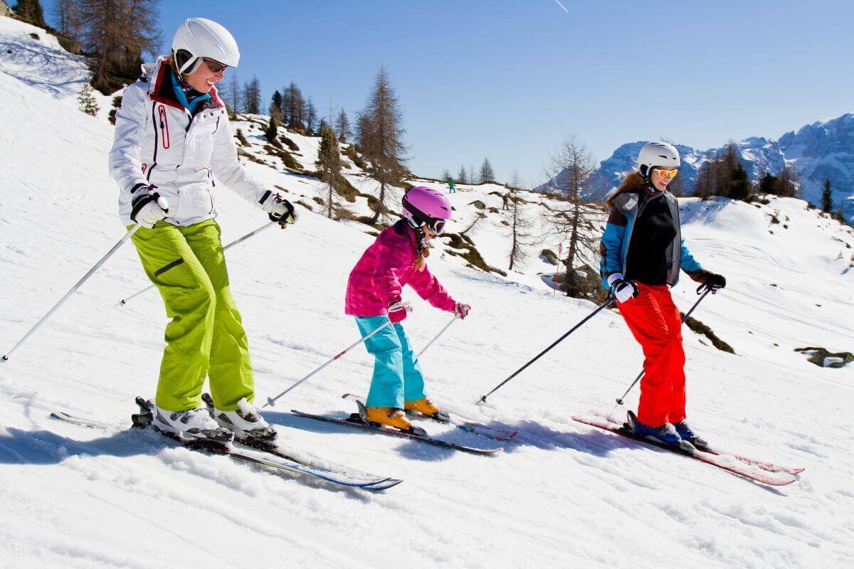 A family skis down a snowy slope during their Montana vacation.
