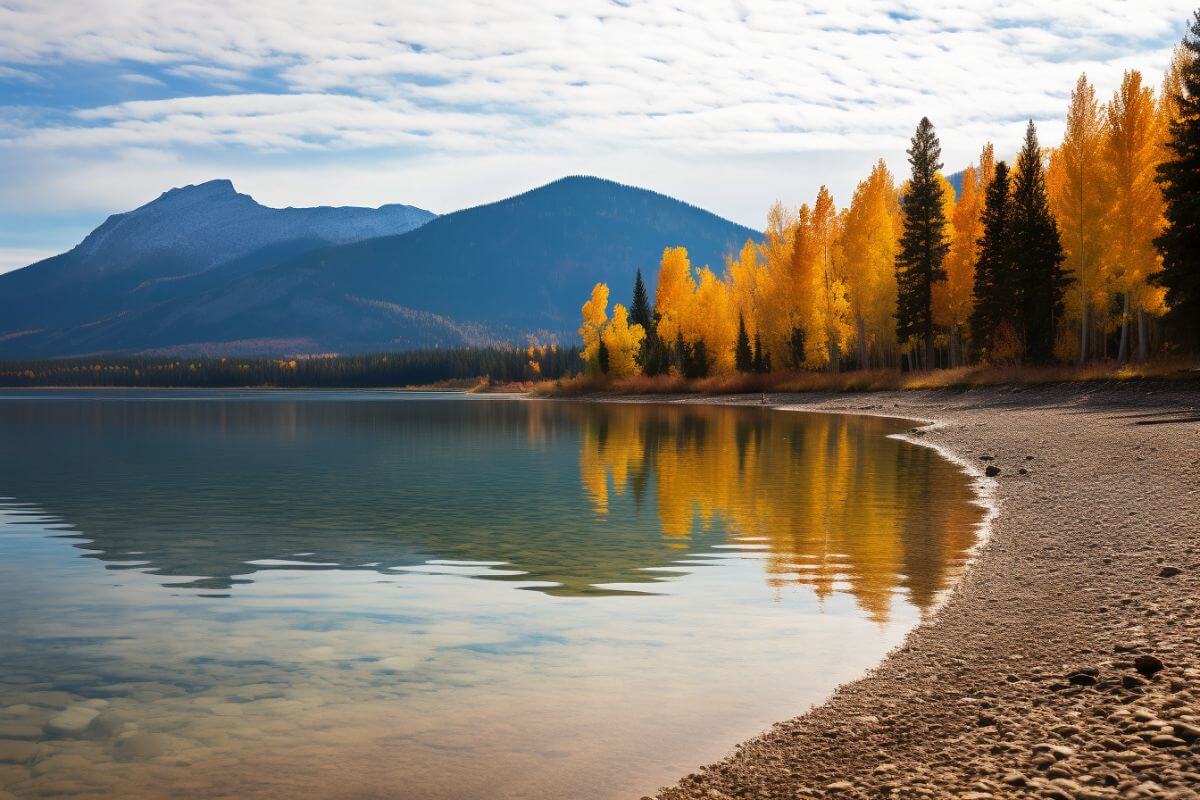 A scenic lake nestled in the midst of towering trees, complemented by majestic mountains presenting a picturesque view of Montana in October.