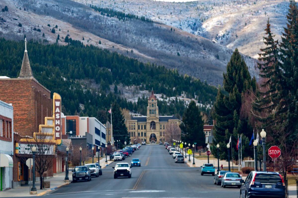 Vehicles parked along the road in a Montana town, with a mountain in the background.