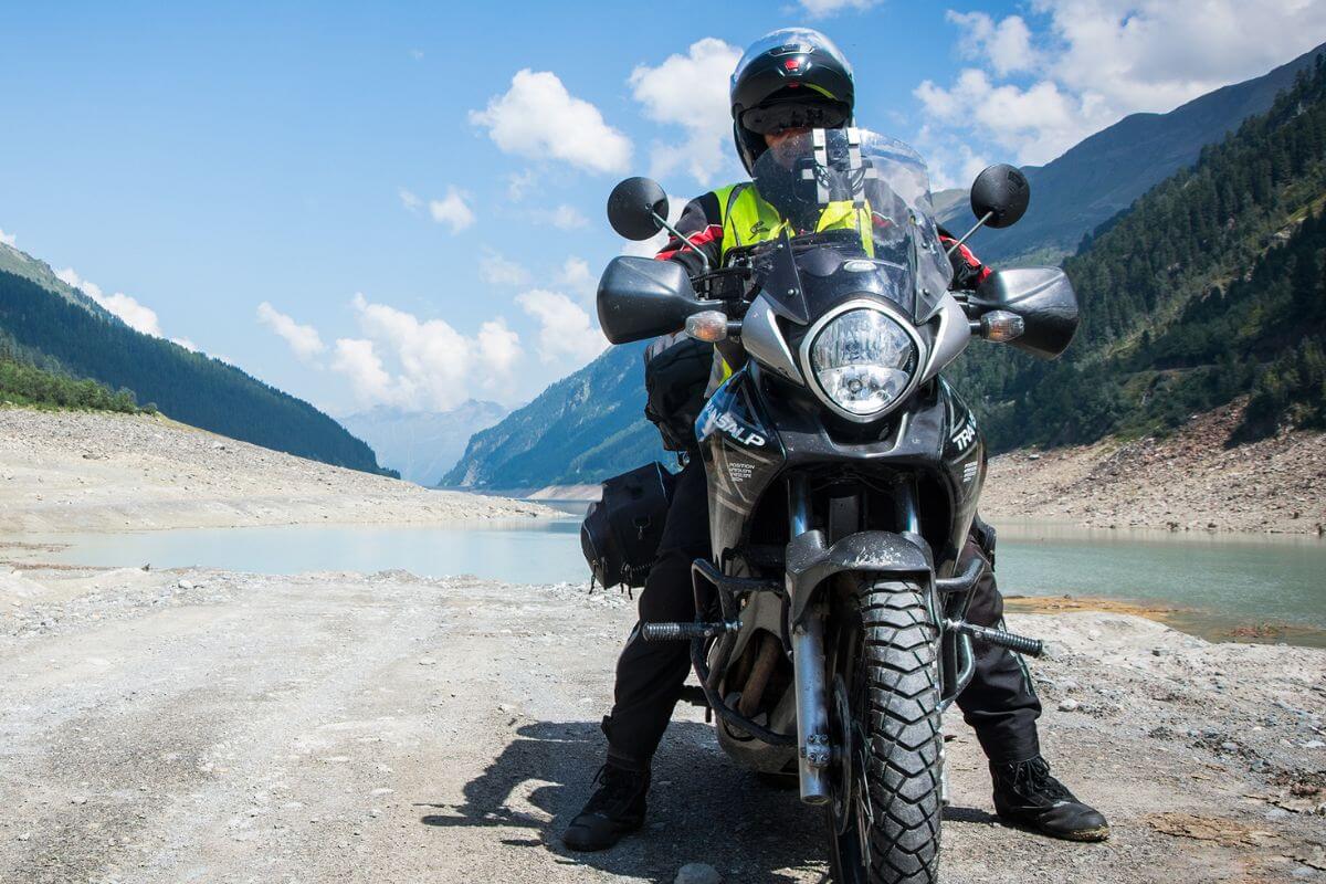 Motorcyclist poised for adventure on a rugged trail with a scenic mountain backdrop.