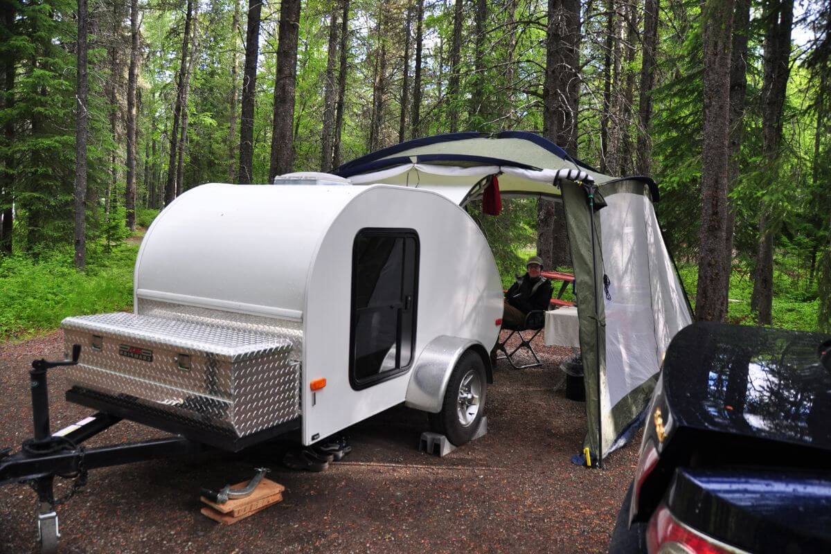 A white camper trailer parked inside an Montana Forest