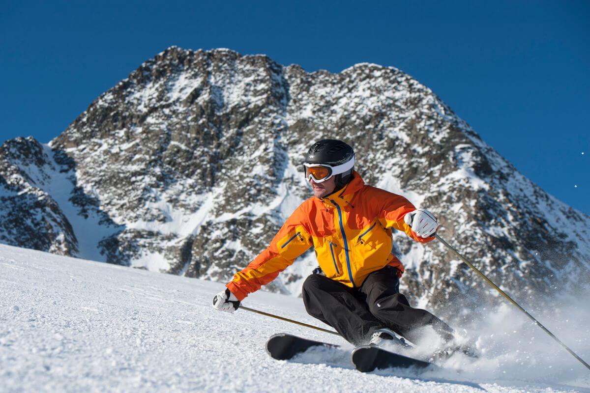 A man skiing down a snowy slope with mountains in the background in Montana.