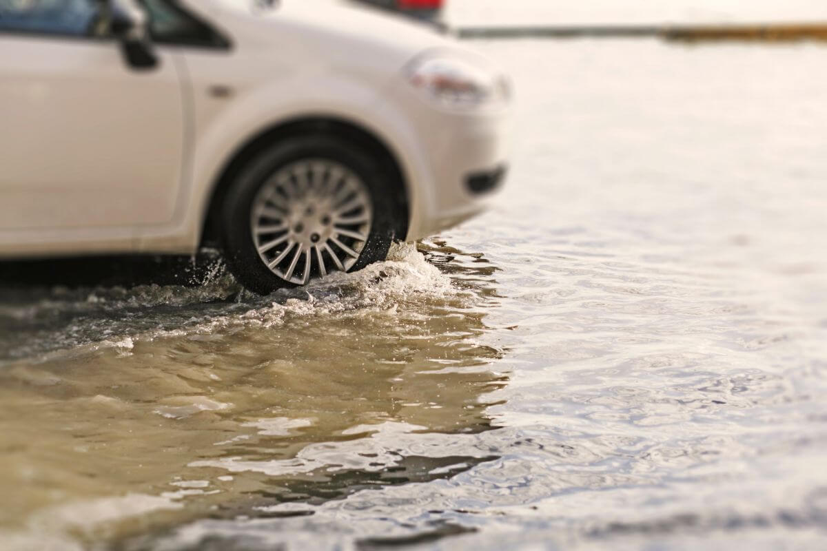 A white car drives through a partially flooded street in Montana