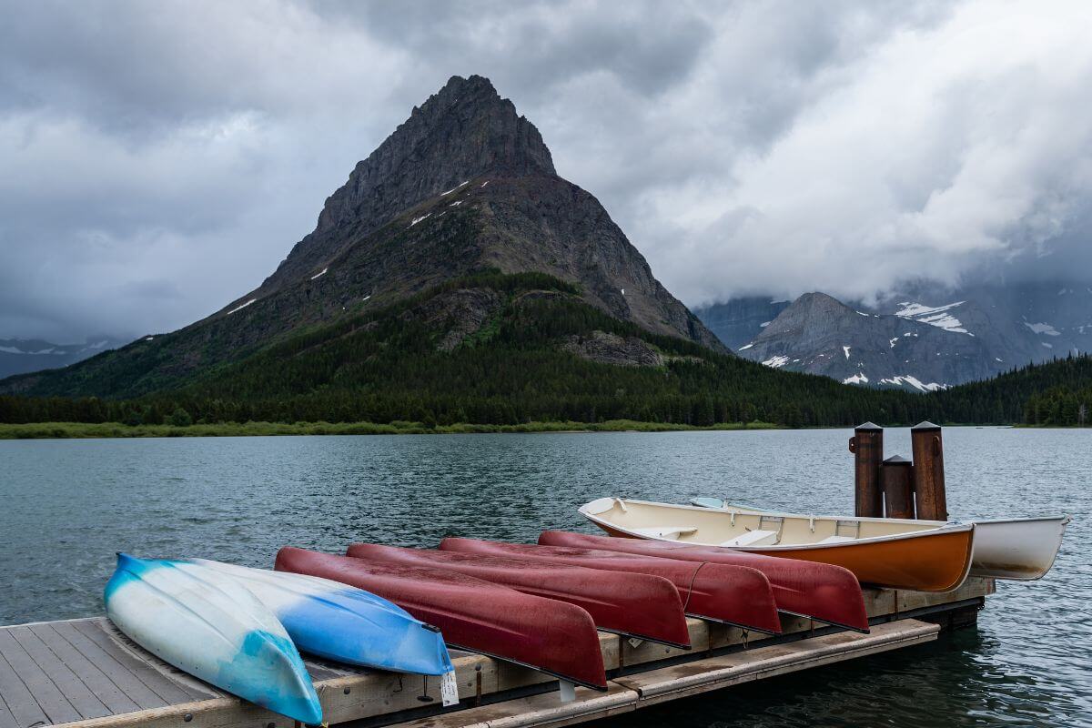 Canoes lined up to dry on the dock of a Montana lake with a mountain in the background.