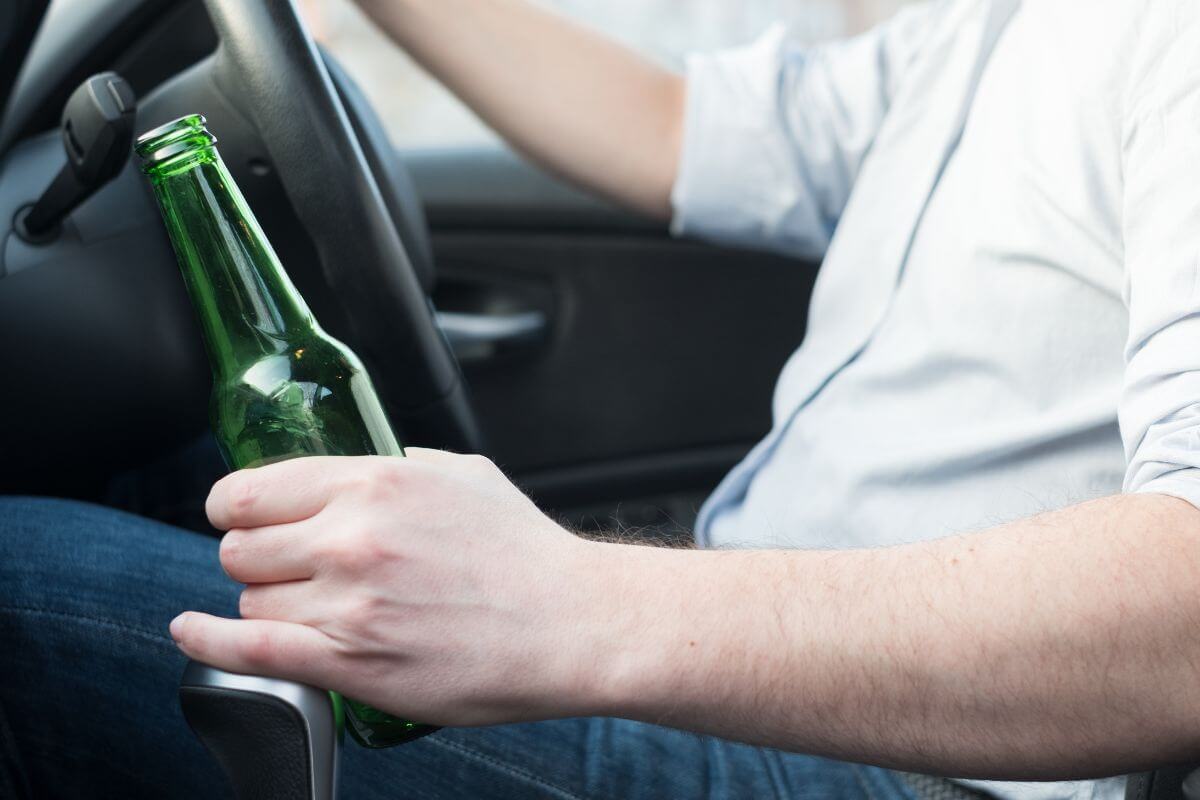 Man Holding an Open Bottle of Beer While Driving