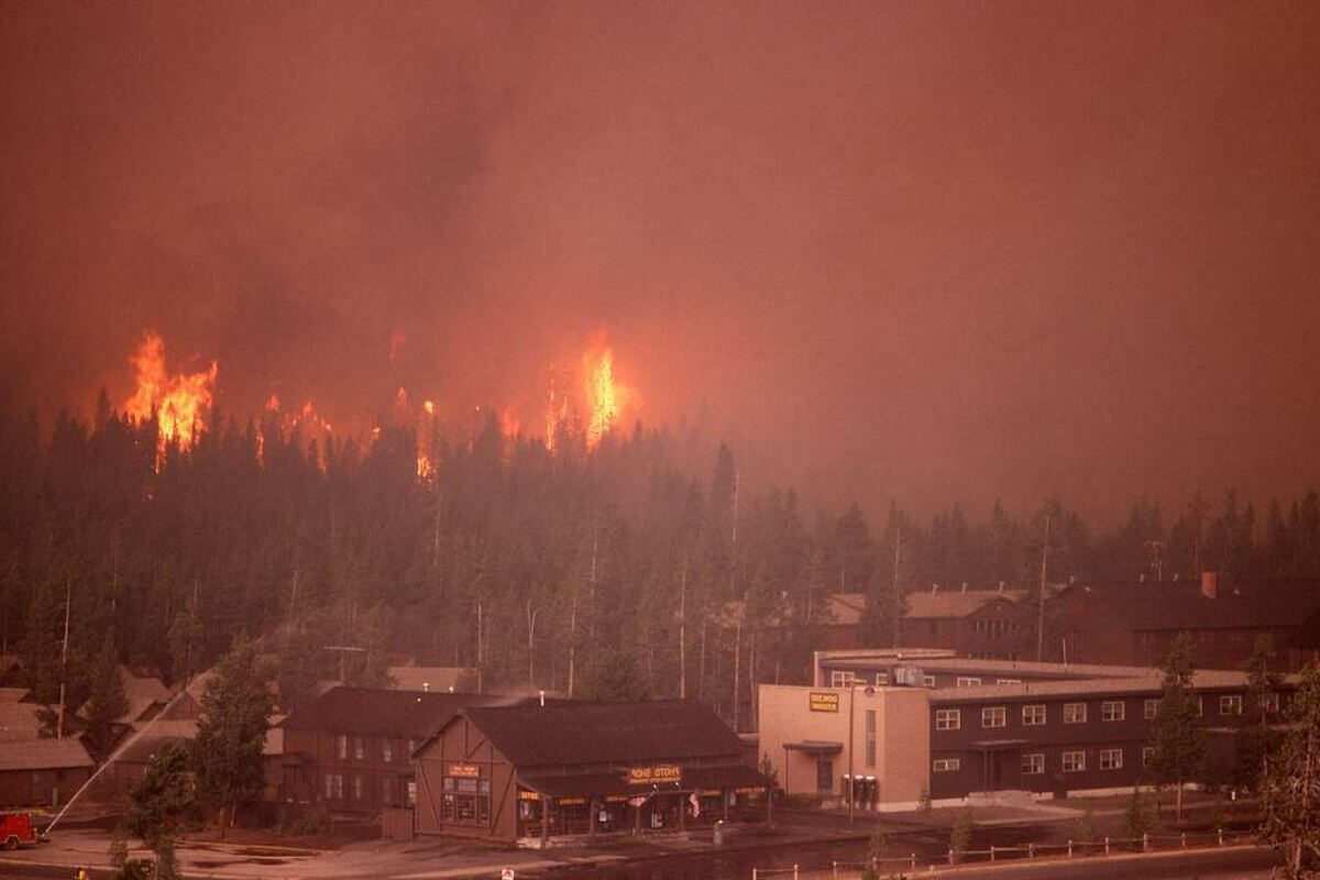 A fire burns through a Montana forest, enveloping a nearby town in heavy smoke.