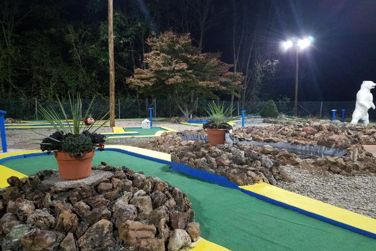 The Valley View Garden Golf mini golf course in Great Falls, Montana seen at night, landscaped with plants and stone paths.