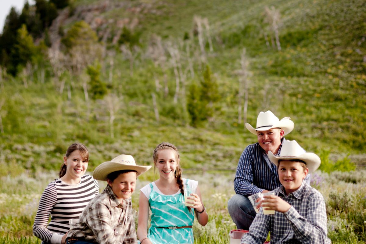 Two parents and their kids are enjoying a picnic in a grassy meadow in Montana.